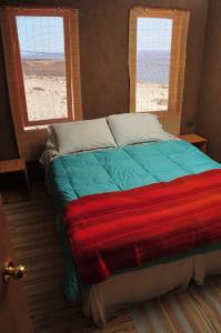 卡尔德拉Hospedaje Boutique Ckamur的一张带五颜六色毯子的床,房间有两个窗户