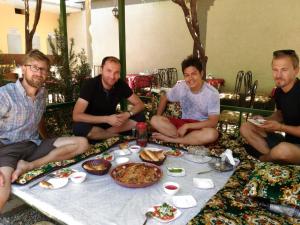 杜尚别City Hostel Dushanbe的一群男人坐在桌子旁吃着食物