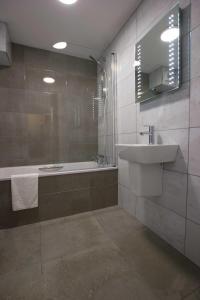 Grouville伯希特酒店 的一间带水槽、浴缸和镜子的浴室