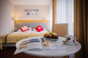 布科维纳-塔钱斯卡HOTEL*** NAT Bukowina Tatrzańska的酒店客房,配有一张床和一张桌子,还有一本书