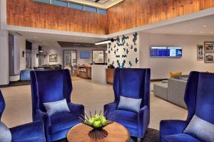 沃里克Hyatt Place Warwick/Providence Airport的一间设有蓝色椅子和桌子的等候室