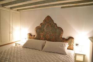 威尼斯卡玛莉酒店的一间卧室配有一张大床和木制床头板