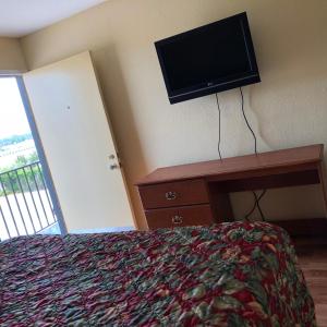 特克萨卡纳Country Host Inn的卧室配有一张床,墙上配有电视。