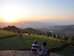 姆杜克Puri Lumbung Cottages Restaurant & Spa Munduk的一群坐在山丘上观看日落的人