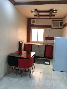 艾卜哈Safwt Aldyar Furnished Units的厨房配有桌椅和冰箱。