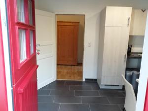 施内沃丁根Apartment am Park - Erica的走廊上设有红色的门和厨房
