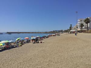 滨海罗克塔斯La Perla Azul Playa - Terraza al Sol的一群人坐在海滩上,拿着遮阳伞