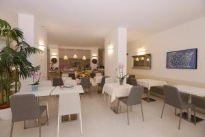 格拉多Hotel & Apartments Eldorado的一间设有白色桌椅的用餐室
