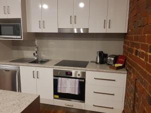旺加拉塔Sublime Spa Apartments的厨房配有白色橱柜和炉灶烤箱。