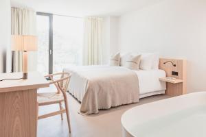 卡斯特尔罗托Schgaguler Hotel的白色卧室配有两张床和一张桌子及椅子