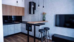 莱格尼察Apartament Wrocławska 29的厨房设有带凳子的酒吧和一台电视机。