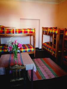 乌尤尼Rummy Hostal的客房设有两张双层床和一张带鲜花的桌子。