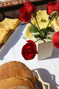 马拉喀什Riad CHERRATA的红玫瑰和花瓶顶的桌子