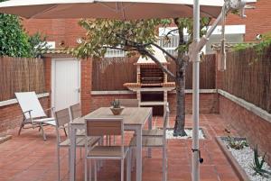 帕拉福尔斯Vivalidays Casa Pinell - Palafolls - Costa Barcelona的露台的遮阳伞下的桌椅