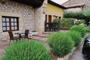 La BustaTrisileja en Posada La Busta的房屋前设有带2把椅子和1张桌子的庭院。