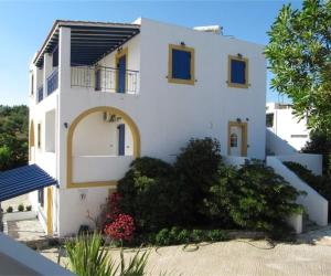 凯瑟拉Petros Studios Kythera的白色的房子,拥有蓝色的窗户和植物