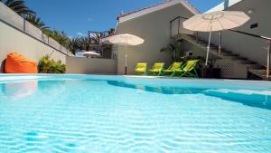 英格兰海滩Villa RG Boutique Hotel - Adults Only的一座房子里一个带椅子和遮阳伞的游泳池