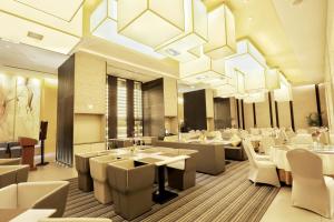 杭州锦江都城杭州市火车东站酒店的餐厅设有白色的桌椅和吊灯。