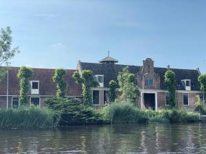 阿姆斯特尔芬HUISJES AAN DE AMSTEL - Your home away from home的河岸上的一座老房子