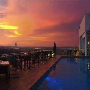 新山Amerin Hotel Johor Bahru的一座享有日落美景的建筑屋顶上的游泳池