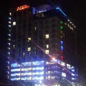 新山Amerin Hotel Johor Bahru的一座高大的建筑,上面有蓝色和绿色的灯光