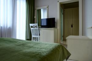普里什蒂纳Hotel Gorenje的一间卧室配有一张床、一台电视和一把椅子