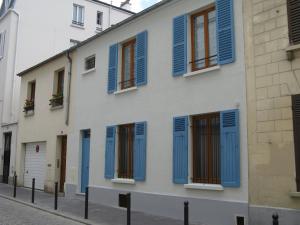 巴黎贝尔维尔酒店的白色的建筑,在街上有蓝色百叶窗