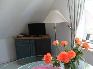 青斯特Cozy Apartment in Zingst Germany with Garden的玻璃桌上带橙花的花瓶
