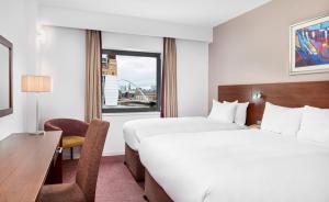 泰恩河畔纽卡斯尔Leonardo Hotel Newcastle Quayside的酒店客房设有两张床、一张书桌和一个窗户。