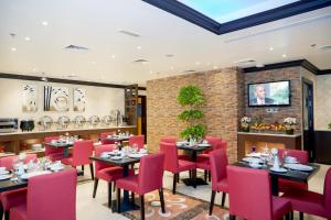 迪拜梦幻城公寓式酒店的用餐室配有桌子和红色椅子