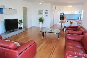 伊齐齐Apartments Anna的客厅配有红色皮革沙发和桌子