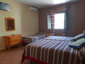 潘潘埃拉Hostal Pampaneira的一间卧室设有两张床、一个梳妆台和窗户。