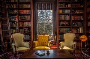 East HamptonThe Bevin House B&B的图书馆,带两把椅子和一张桌子,还有一个窗口