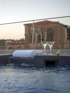 罗希姆诺Mediterraneo Suite Home的游泳池上摆放着两只马提尼玻璃杯