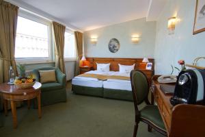 波茨坦阿姆路易森广场酒店的酒店客房配有一张床铺、一张桌子和一张书桌。