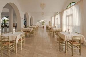 科斯镇亚历山德拉海滩酒店的一间设有白色桌椅的用餐室