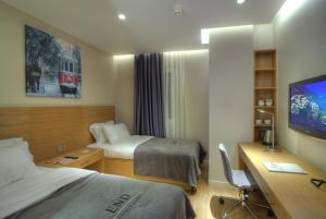 伊斯坦布尔塔克辛超多套房酒店的酒店客房设有两张床、一张桌子和一台电视。