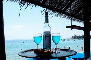 勒拉旺杜Hôtel的海滩上的一张桌子上放着一瓶葡萄酒和两杯酒