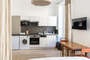 罗什福尔les appartements du 10的厨房配有白色橱柜、洗衣机和烘干机