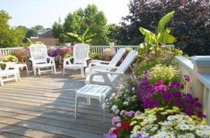 纽波特洋基佩德勒旅馆的一组白色椅子,坐在开满鲜花的甲板上