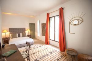 马拉喀什Riad Alia的一间卧室配有一张床、一张桌子和一个窗户。
