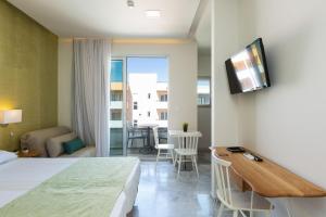 罗希姆诺Meltemi Coast Suites的酒店客房设有床、桌子和电视。