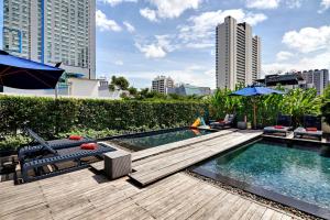 曼谷Fraser Suites Sukhumvit Bangkok的一座游泳池,设有一座毗邻城市的木甲板