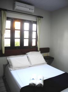 纳塔尔普拉亚公寓酒店的一间卧室配有一张带白色床单的床和一扇窗户。