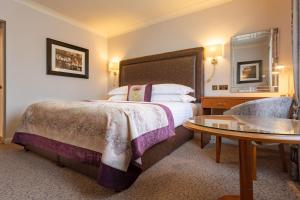 埃文河畔斯特拉特福Swan's Nest Hotel的酒店客房配有一张床铺和一张桌子。