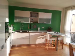 维琴察Residenza San Pietro的绿色厨房配有白色橱柜和桌子