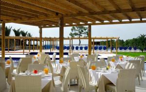 基内塔Kinetta Beach Resort and Spa的一组桌椅,配有白色的桌子和白色的椅子