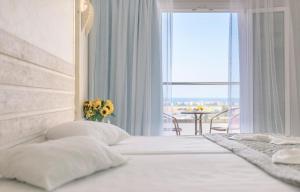 毕达哥利翁萨摩斯太阳酒店的一间卧室配有一张带窗户和桌子的床