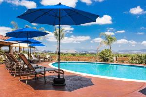 蒂梅丘拉卡特酒庄度假酒店的一个带椅子和遮阳伞的游泳池和一个游泳池