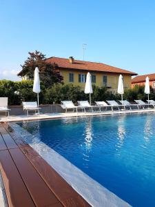 阿斯蒂Locanda Ferro UNO, Golf Città di Asti的一个带躺椅和白色遮阳伞的游泳池